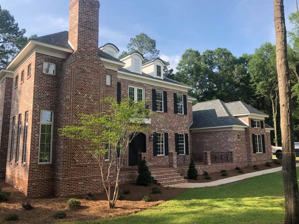 Front of large brick colonial with herringbone detail and dormers