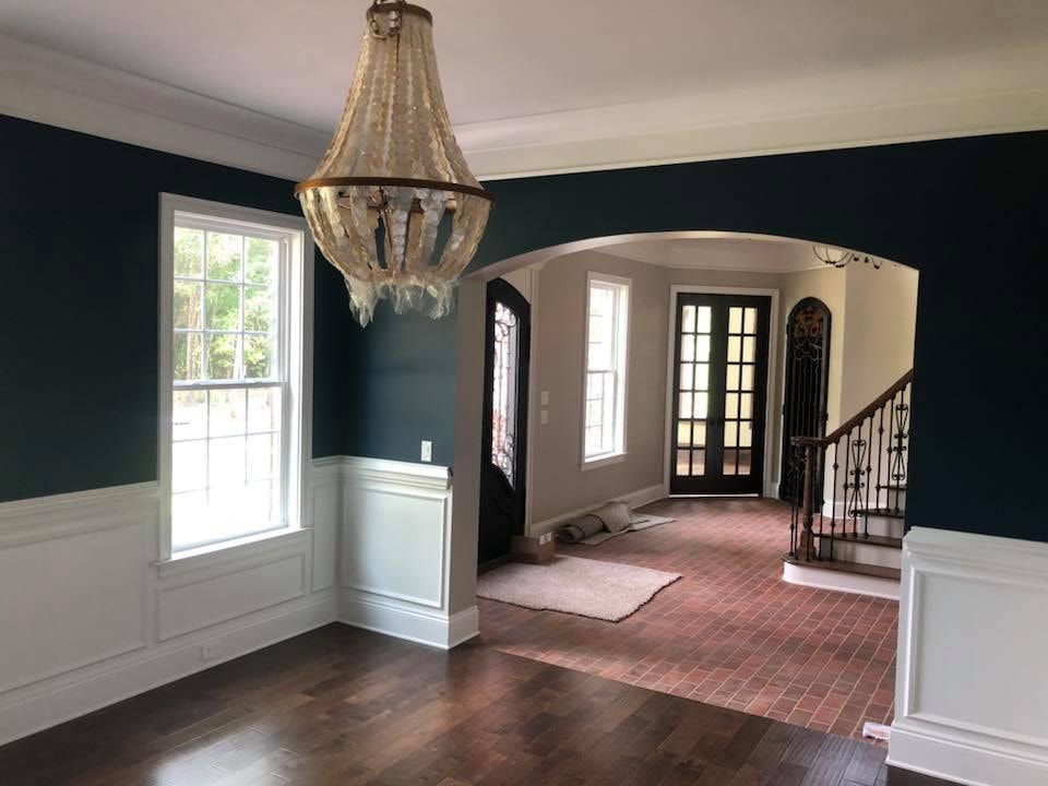 Dining room with teal walls, wainscoting, chandelier and arched entry