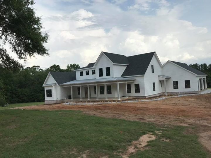 White farmhouse with wraparound porch and maturing lawn