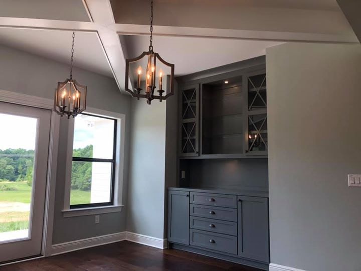 Gray built-in hutch with glass doors, coffered ceiling and lantern pendants
