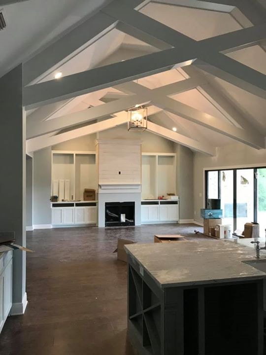 Great room under construction showing vaulted X-beam ceiling and built-in shelving