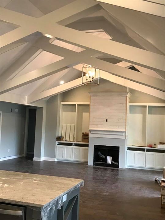Great room with vaulted X-beam ceiling, shiplap fireplace and dark hardwood floors