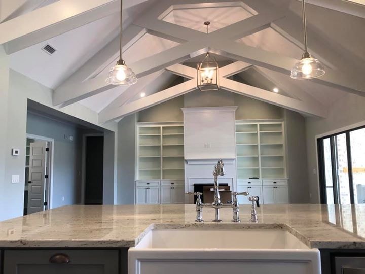 Vaulted X-beam ceiling from island with built-in shelving flanking fireplace