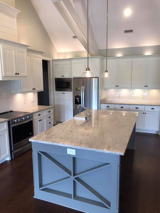 White kitchen with vaulted ceiling, gray X-detail island and stainless appliances