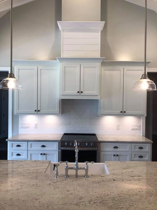 White shaker cabinets with shiplap range hood, subway tile and bridge faucet