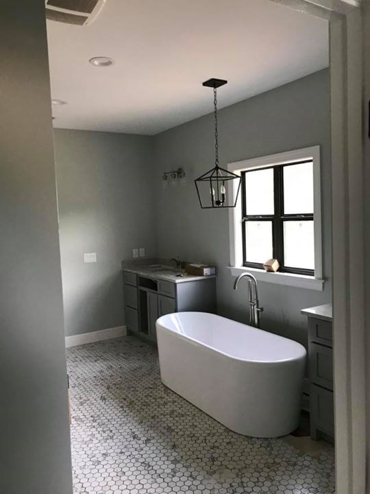 Master bath under construction with freestanding tub, lantern pendant and hex tile floor