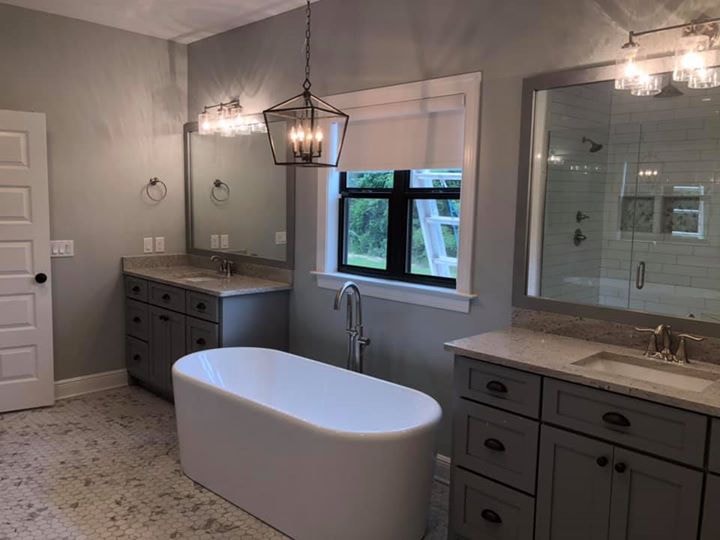 Finished master bath with freestanding tub, dual gray vanities, lantern pendant and hex tile