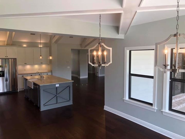 Open kitchen and living area with gray X-detail island, coffered ceiling and dark hardwood