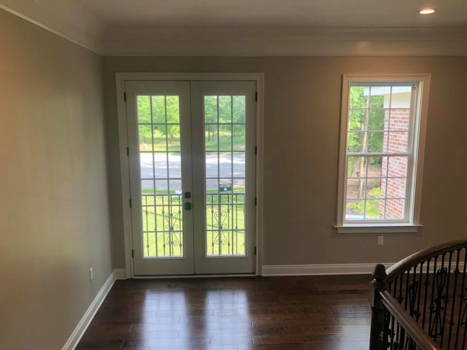 Room with French doors, hardwood floors and wrought-iron stair rail