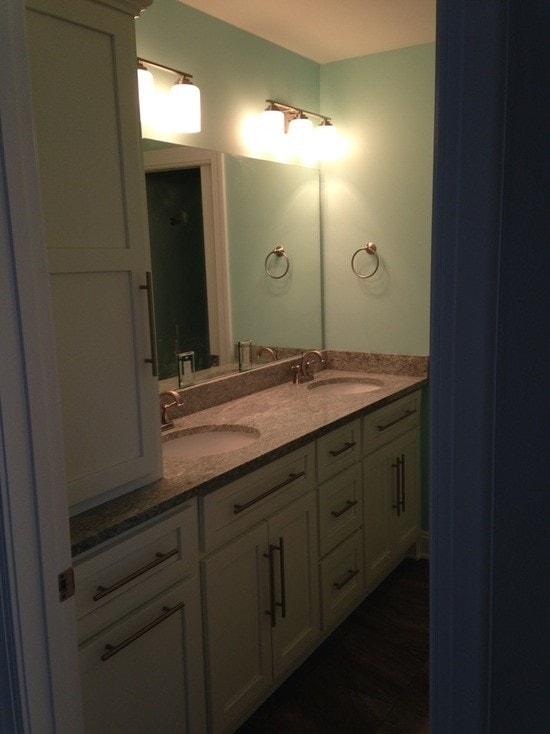 Bathroom with teal walls, white cabinetry, gray granite double vanity and brushed nickel fixtures