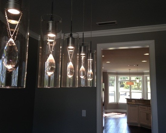 Dramatic crystal pendant cluster in dining area with dark walls and view through to kitchen with bay window