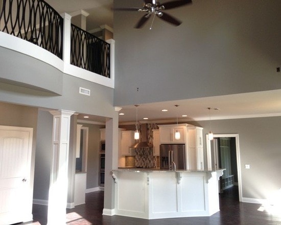 Two-story open plan great room with white kitchen island, pendant lights, stainless fridge and ornate loft railing