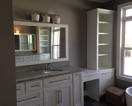 Master bath vanity close-up with white cabinetry, gray granite, framed mirror and open tower shelving