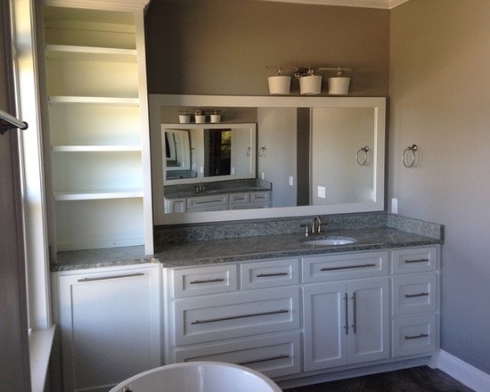 Master bath wide view with white cabinetry, gray granite vanity, framed mirror, open tower shelving and freestanding tub