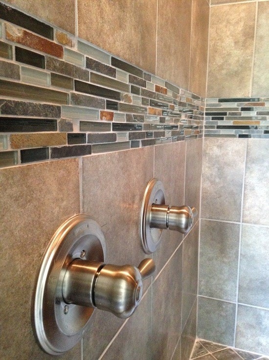 Shower with taupe large-format tile, multi-color linear glass and stone mosaic accent band and brushed nickel valve trim