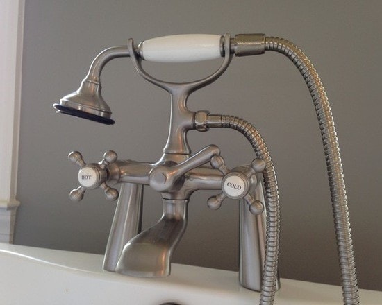 Vintage-style brushed nickel floor-mount tub faucet with cross handles labeled HOT and COLD and handheld shower
