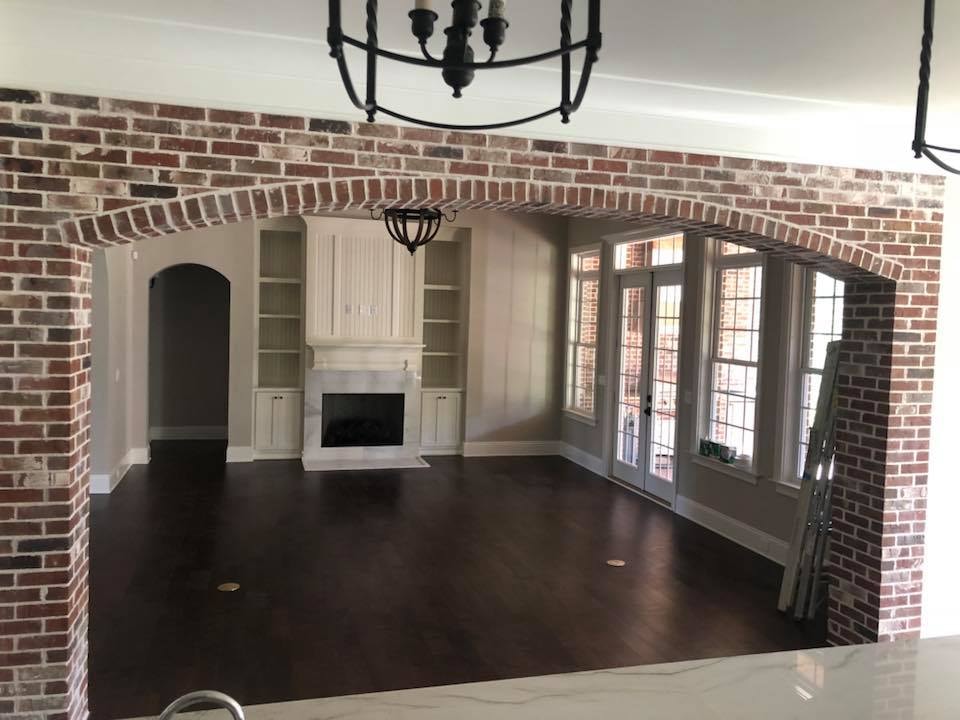 Great room with brick arched opening, fireplace wall and French doors