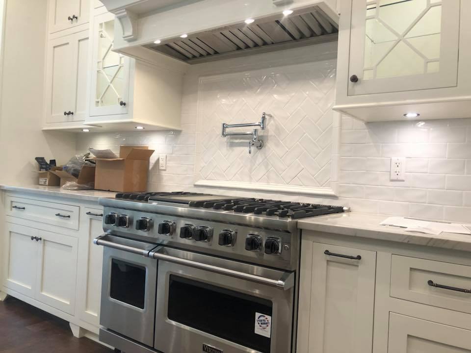 Close-up of Viking range with herringbone tile and custom range hood