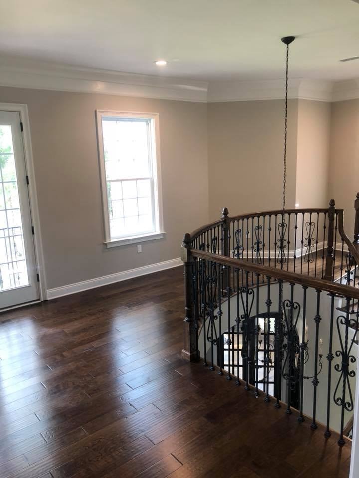 Upper loft hallway with dark hardwood floors and iron railing