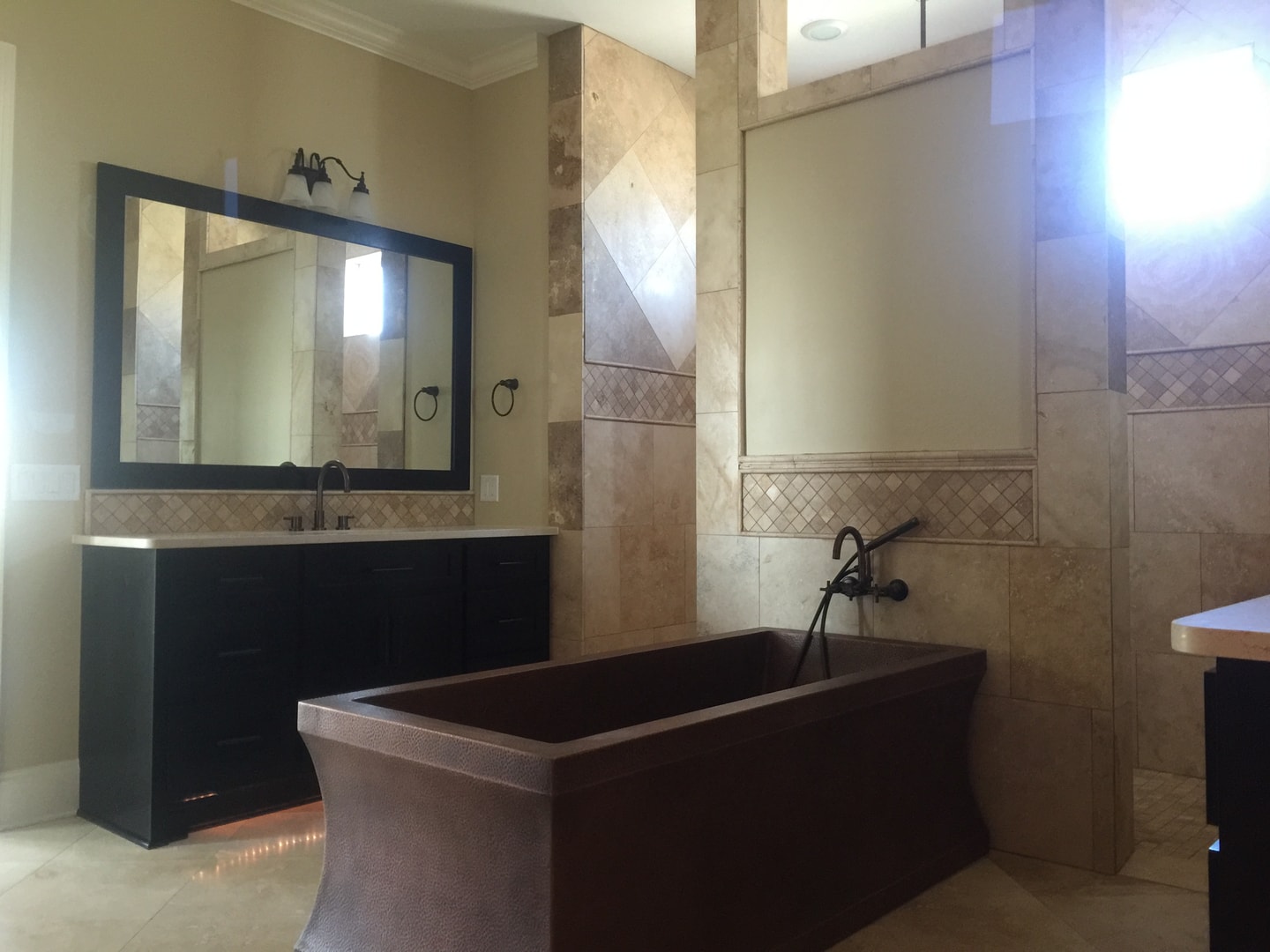 Master bath with hammered copper freestanding tub, travertine tile and dark vanity