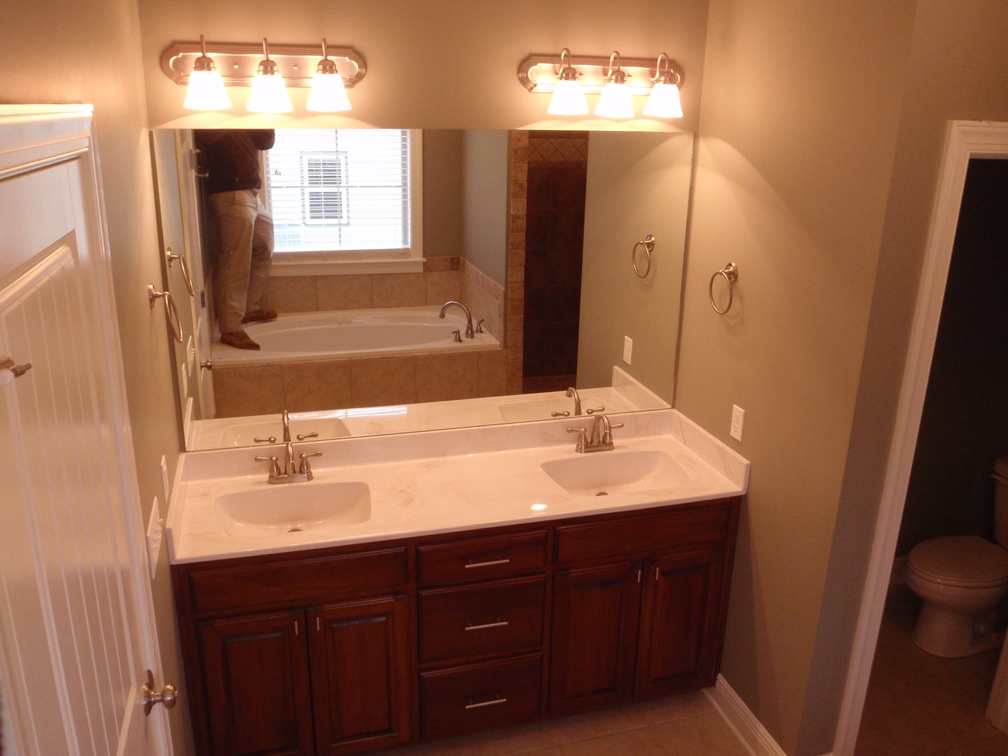Master bath double vanity with cherry cabinetry, white cultured marble counter and Hollywood lighting