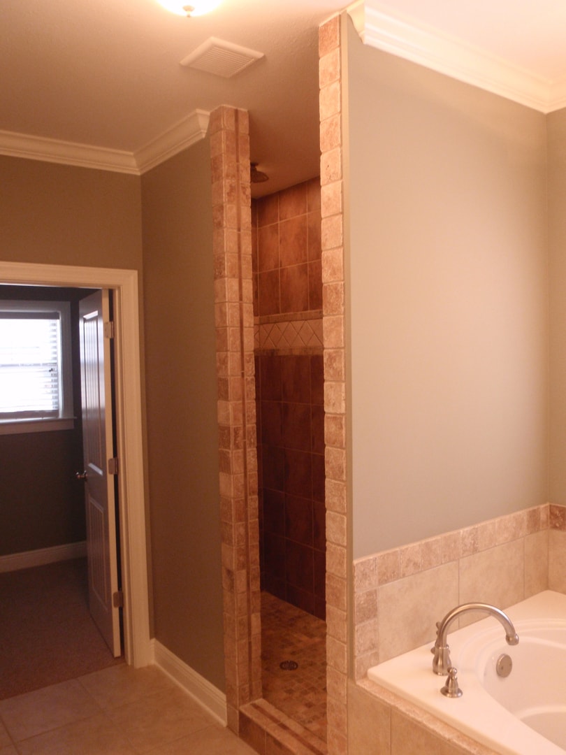 Master bath with stacked stone shower entry, drop-in tub with tile surround and crown molding