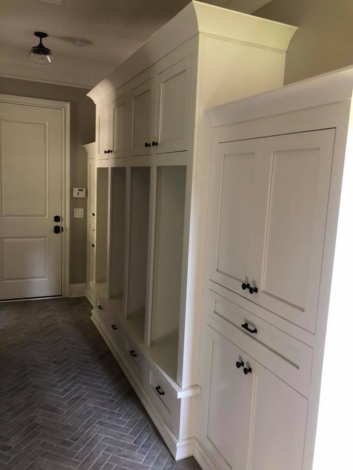Mudroom with white custom cabinetry and herringbone tile floor