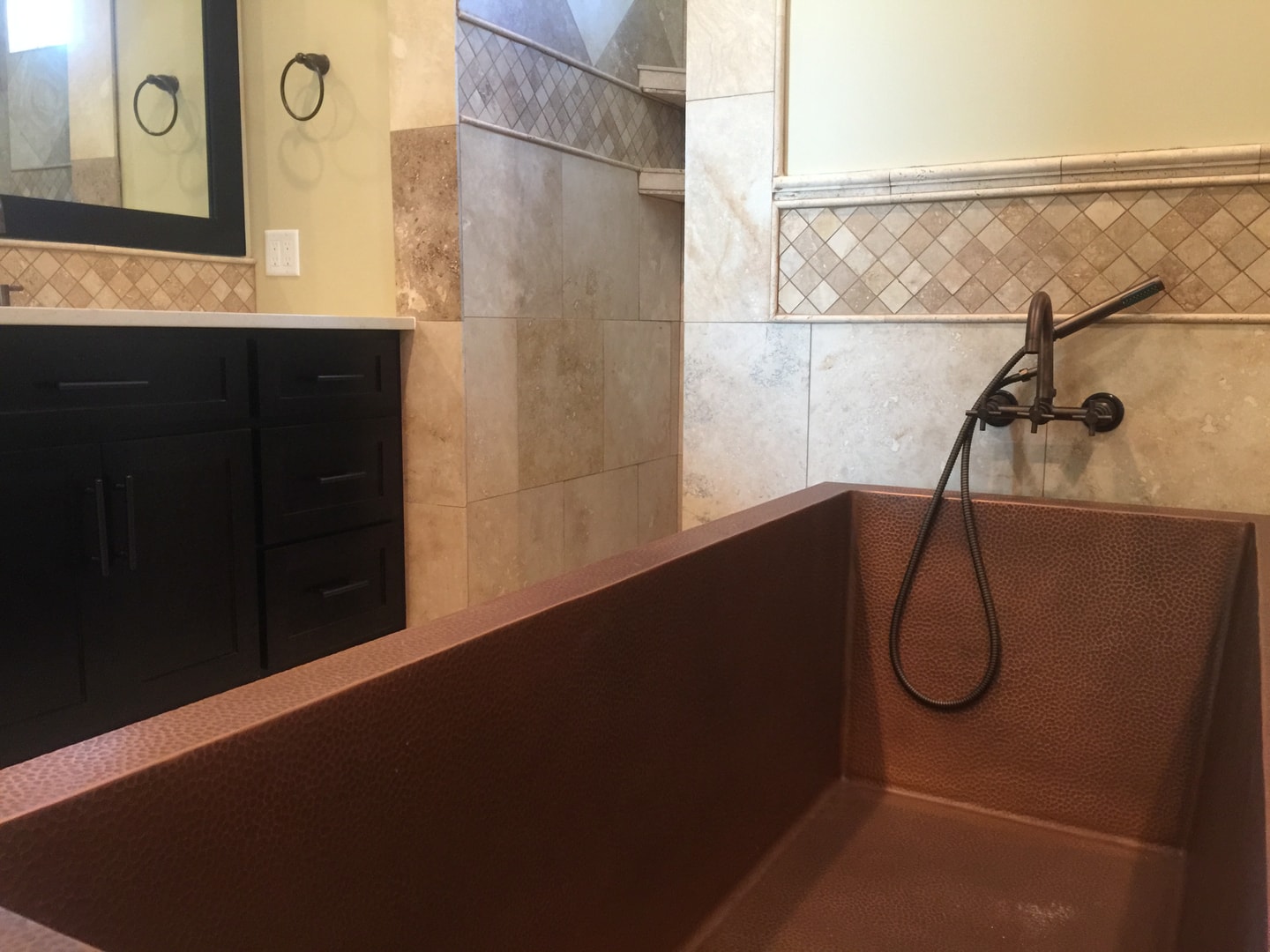 Hammered copper rectangular soaking tub with wall-mount faucet and dark vanity
