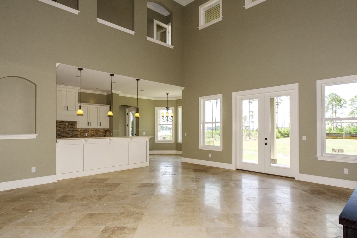 Open plan living and kitchen with sage walls, white island, pendant lights and French doors to yard