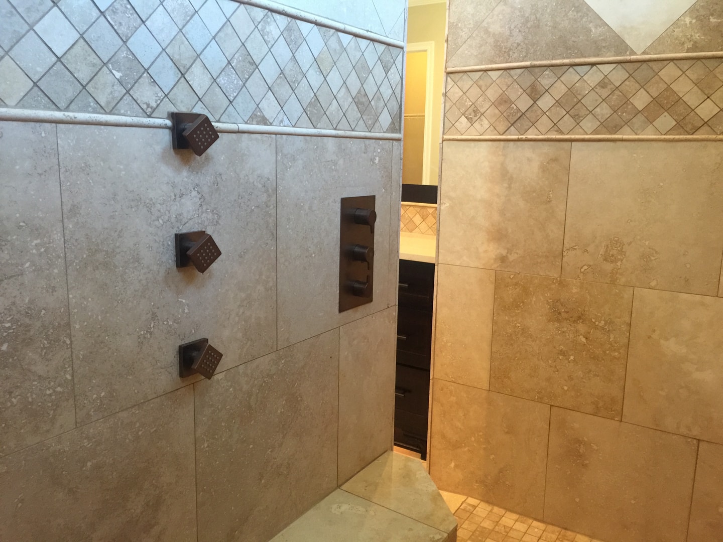 Travertine shower with diamond mosaic border, oil-rubbed bronze body jets and thermostatic valve