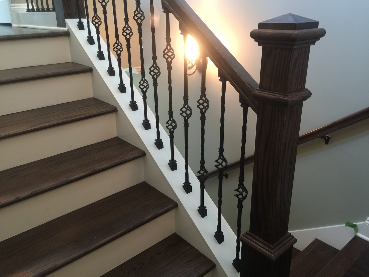 Staircase with dark wood treads, white risers and ornate wrought-iron balusters