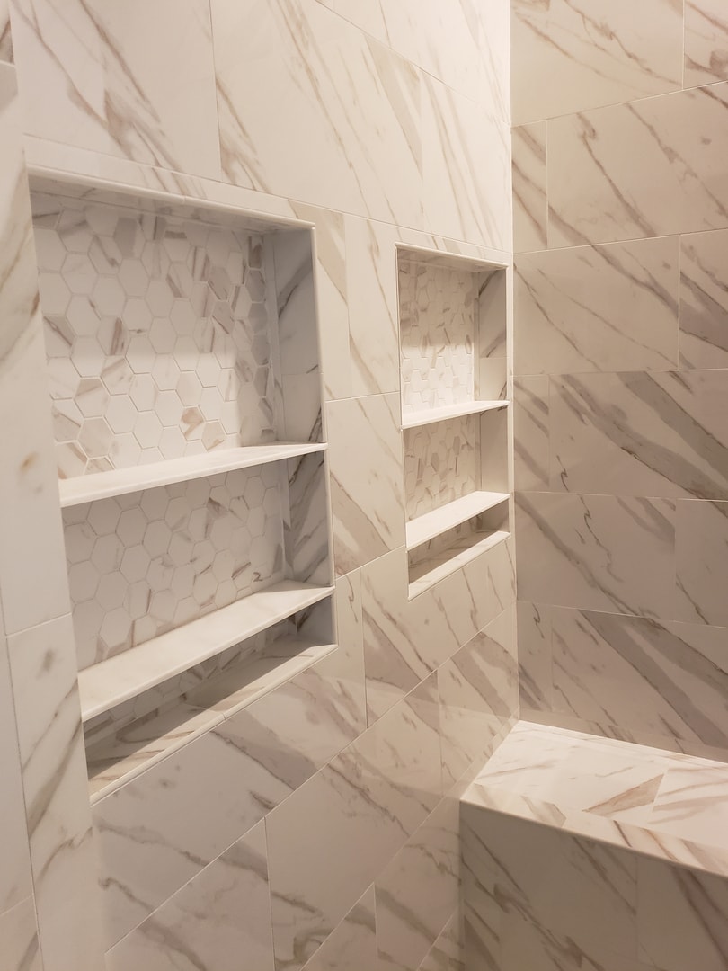Marble shower with built-in niches, hexagon mosaic insets and bench