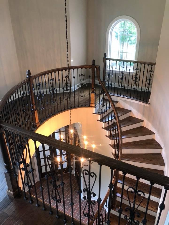 Grand spiral staircase with wrought-iron railings and chandelier