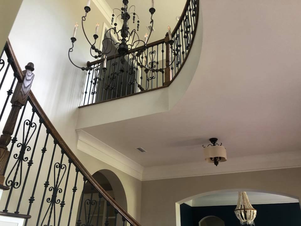Two-story staircase with chandelier and wrought-iron railings