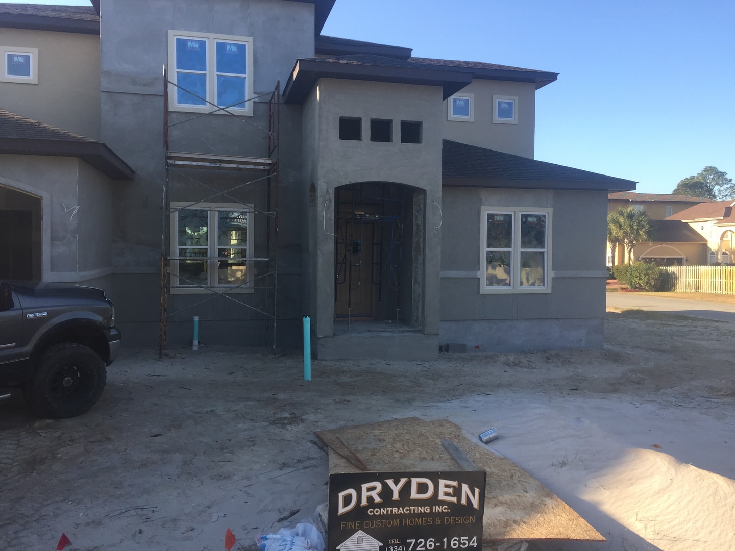 Stucco home in early construction phase with Dryden Contracting sign in foreground