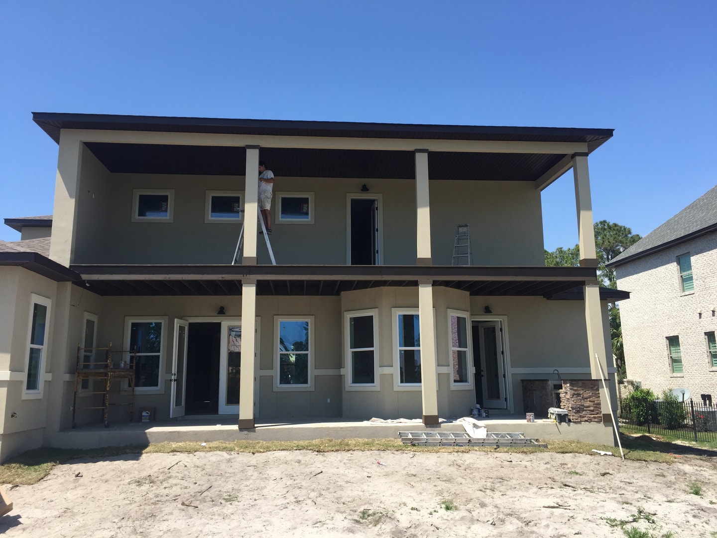 Rear of two-story stucco home under construction with double-decker covered porches