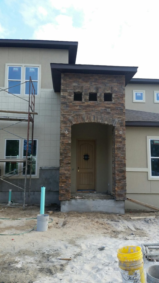 Close-up of stacked stone arch entry tower with wood door under construction