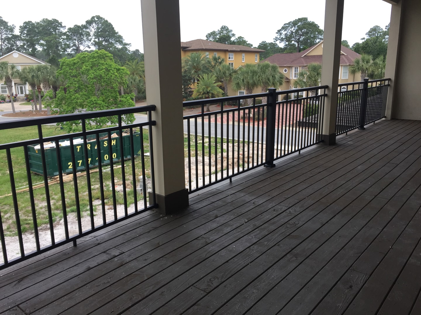 Upper deck with dark hardwood flooring, black aluminum railing and palm tree neighborhood view